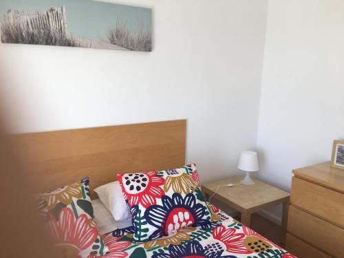 een slaapkamer met een bed met kleurrijke kussens erop bij Apartamento em frente ao Mar in Vila do Conde