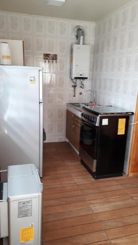 a kitchen with a stove and a refrigerator at Cabañas Nortesur in Coihaique