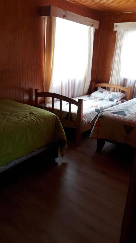 1 dormitorio con 2 camas y ventana en Cabañas Nortesur, en Coyhaique