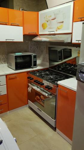 a kitchen with orange cabinets and a stove top oven at Mansoura apartment infront of KFC in Mansoura