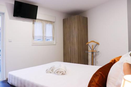 a bedroom with a bed with white sheets and a television at Casa Nossominho in Vila Nova de Cerveira