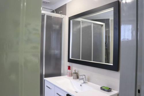 a bathroom with a sink and a mirror and a shower at Casa Nossominho in Vila Nova de Cerveira