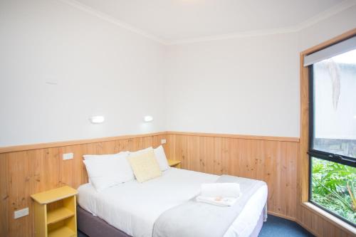 a bedroom with a white bed and a window at Thou Walla Sunset Retreat in Soldiers Point