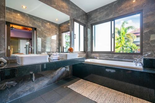 a bathroom with two sinks and a tub and a large window at Jewels Villas Phuket in Bang Tao Beach