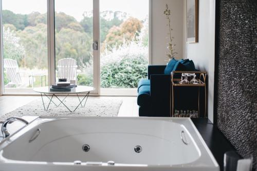 bañera blanca en la sala de estar con ventana en Polperro Villas, en Red Hill