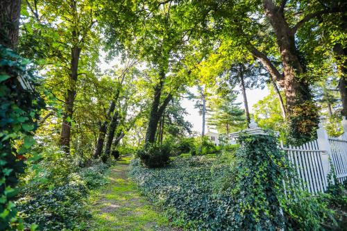 un jardín con una valla blanca y árboles en Niagara Mansion Carriage Suite en Lewiston