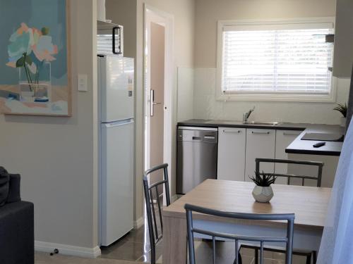 a kitchen with a table and a white refrigerator at Rose Apartments Unit 6 Central Rotorua-Accommodation & Spa in Rotorua