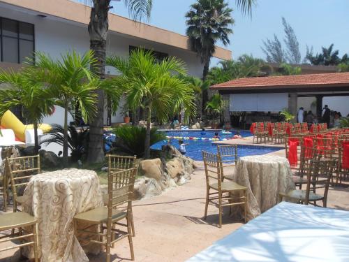 a pool with tables and chairs in front of a resort at Hotel Poza Rica Inn in Poza Rica de Hidalgo