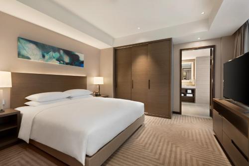 a bedroom with a large white bed and a flat screen tv at Hyatt House Chengdu Pebble Walk in Chengdu
