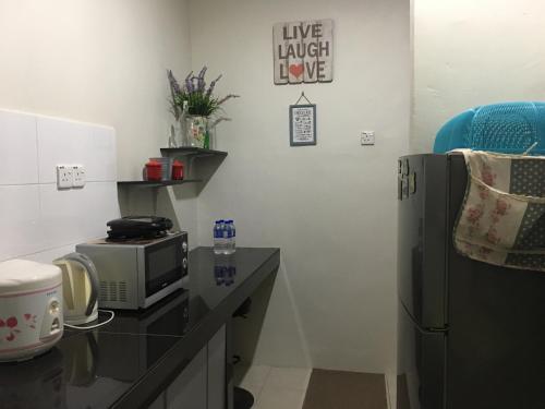 a kitchen with a microwave and a refrigerator at Miker Homestay in Seri Iskandar