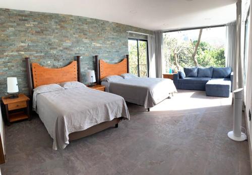 a bedroom with two beds and a brick wall at Casa de las Aves - Alberca y Jacuzzi climatizados - Espectaculares vistas in Malinalco