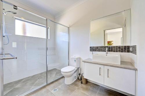 a bathroom with a toilet and a sink and a shower at Woodgate Beach Houses in Woodgate