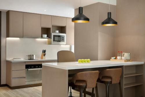 a kitchen with a kitchen island with chairs and appliances at Hyatt House Chengdu Pebble Walk in Chengdu