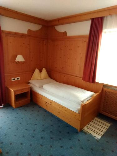 a wooden bed in a room with a window at La Cianò in Corvara in Badia