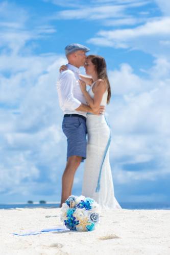 a bride and groom kissing on the beach at Beach Villa Ukulhas in Ukulhas
