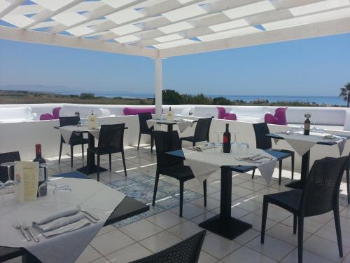 un restaurante con mesas blancas y sillas en la azotea en Zahira Resort, en Tre Fontane