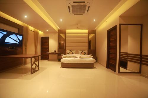 a bedroom with a bed and a desk and a television at Hotel Le Grande in Jaipur
