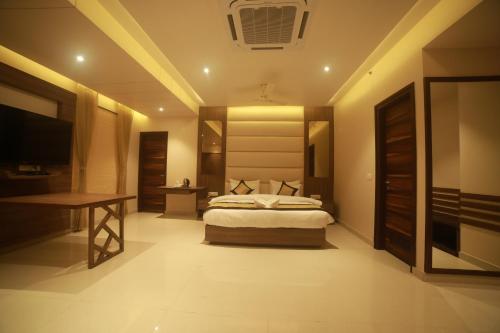 a bedroom with a bed and a desk and a television at Hotel Le Grande in Jaipur