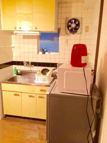 a kitchen with a microwave on top of a refrigerator at Casa Viento Stay Inn in Hiroshima