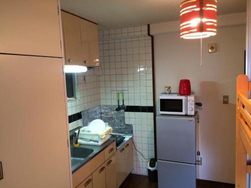 a small kitchen with a refrigerator and a microwave at Casa Viento Stay Inn in Hiroshima