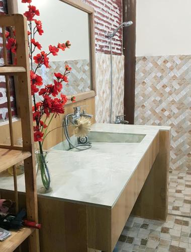 a bathroom with a sink and a vase with red flowers at Tien Yoga House in Cái Bè
