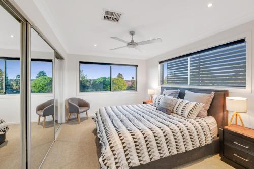 a bedroom with a bed and two windows at Fairway Village @ Windaroo Lakes Golf Club in Windaroo