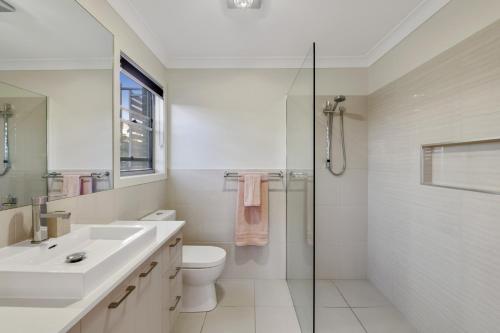 a bathroom with a toilet and a sink and a shower at Fairway Village @ Windaroo Lakes Golf Club in Windaroo