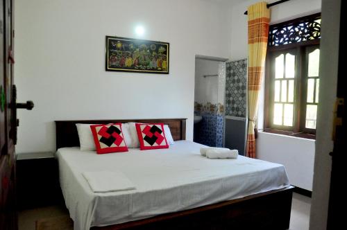 a bedroom with a bed with red and black pillows at Little Swan Guest house in Bentota