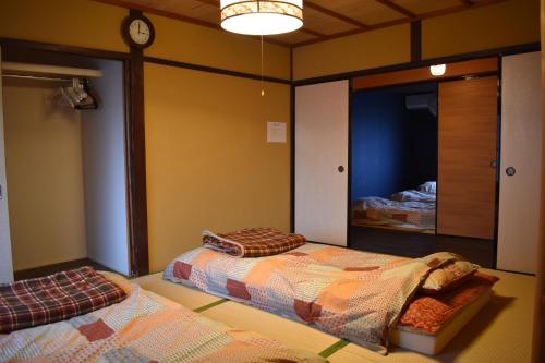 a bedroom with two beds and a clock on the wall at Nishioji KADO 西大路 角 わんちゃんと泊まれるお宿 in Kyoto