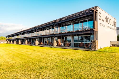 a building with a grass field in front of it at Suncourt Hotel & Conference Centre in Taupo