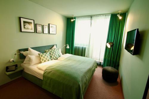a bedroom with a bed with green curtains and a window at Hotel Metropol by Maier Privathotels in Munich