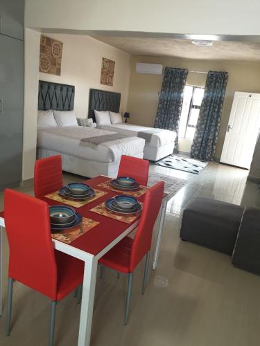 een woonkamer met een tafel, stoelen en een bed bij MATAT GARDENS in Matatiele