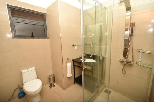 a bathroom with a toilet and a glass shower at Bukoto Heights Apartments in Kampala