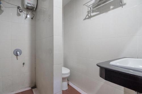 a white bathroom with a toilet and a sink at RedDoorz Syariah near Jamtos Jambi in Jambi