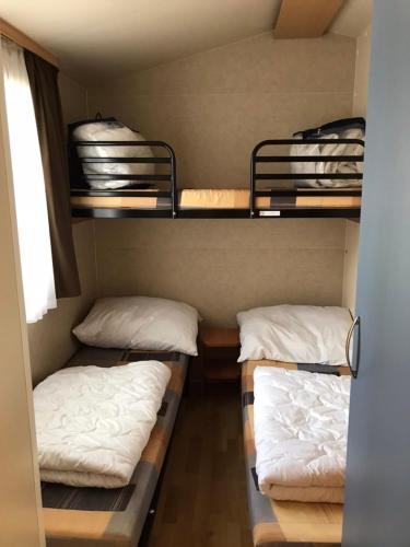 a room with three bunk beds in a room at SunVillage Camp- Mobilházak Alsóörsön in Alsóörs