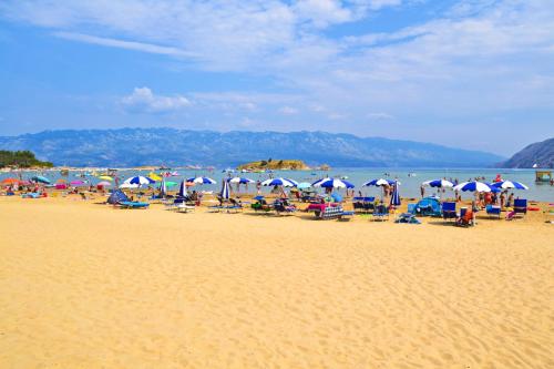 una playa con muchas sillas y sombrillas. en San Marino Camping Resort by Valamar, en Lopar