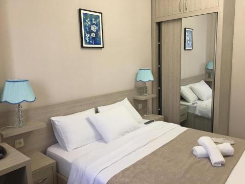 a bedroom with a large bed with two lamps and a mirror at Family Hotel Triston in Tbilisi City