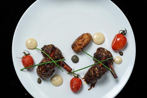 a plate of food with meat and tomatoes on it at Amirey Hagalil Boutique Hotel in Amirim