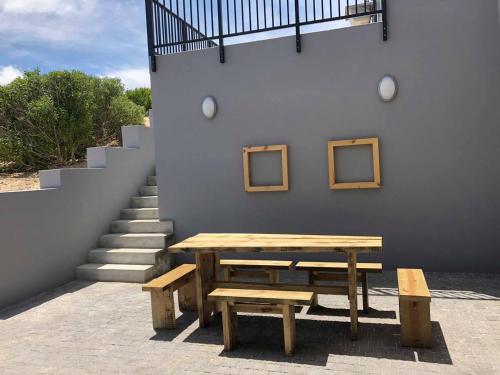 a picnic table and two benches next to a staircase at Still Bay East Beach Apartment in Stilbaai