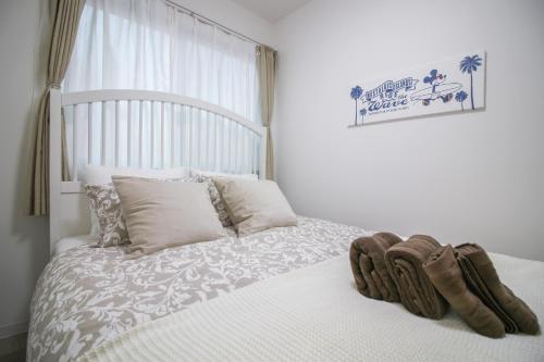 a bedroom with a white bed with shoes on it at CASA Higashi Mikuni 02 in Osaka