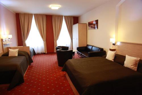 a hotel room with two beds and a chair at Pension Dvořák in Karlovy Vary