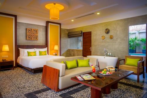 a hotel room with a bed and a couch and a table at Sabara Angkor Resort & Spa in Siem Reap