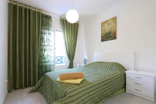 - une chambre avec un lit doté de rideaux verts et d'une fenêtre dans l'établissement Polis Beach Village, à Pólis Chrysochoús