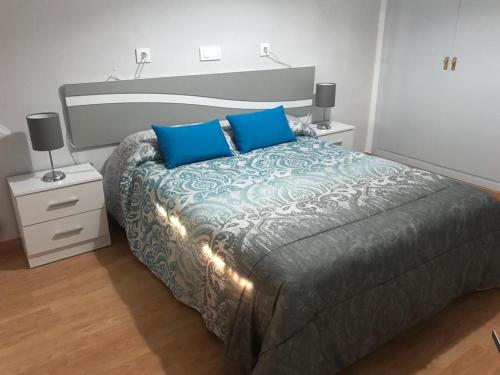 1 dormitorio con 1 cama grande con almohadas azules en Hostal Restaurante Milenium, en Torremegía