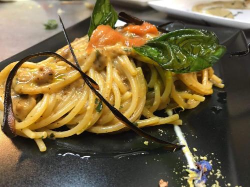 un piatto di pasta su un piatto nero di Dammuso Ziloto a Pantelleria