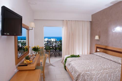 sypialnia z łóżkiem i stołem z telewizorem w obiekcie Grand Hotel Holiday Resort w mieście Hersonissos