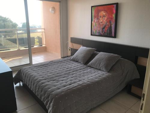 une chambre avec un lit avec un tableau sur le mur dans l'établissement Appartement Face Mer, Piscine, à Canet