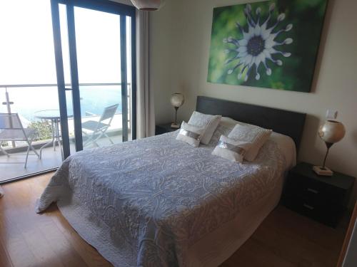 Schlafzimmer mit einem Bett und Blick auf einen Balkon in der Unterkunft Loreto Luxury in Arco da Calheta
