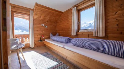 ein Zimmer mit einem Bett in einem Holzzimmer mit zwei Fenstern in der Unterkunft Ferienhaus Sternhof in Mieders