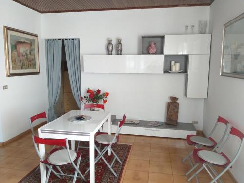 a dining room with a white table and red chairs at Il giardinetto in Premariacco